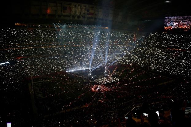 Große Menschenmenge in einem hell erleuchteten Stadion bei Nacht, mit einem Bildschirm auf der rechten Seite, der die Ergebnisse der Super Bowl XLVII Halbzeit zeigt.