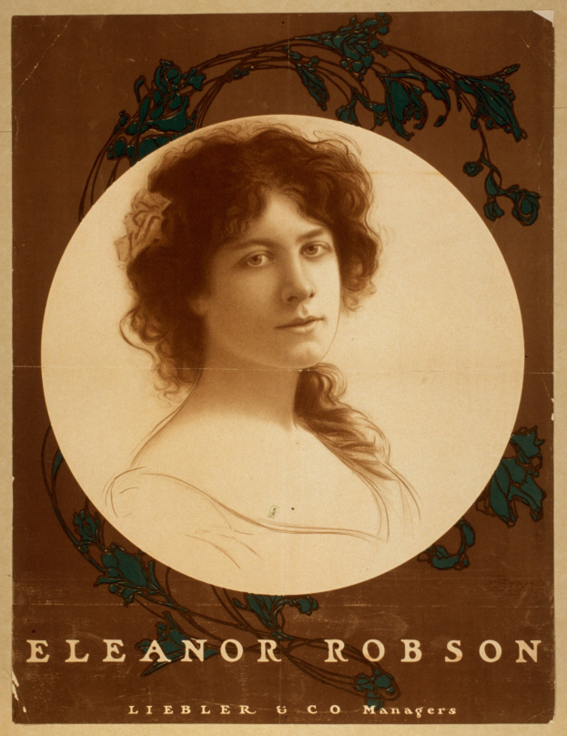 Ein Schwarz-Weiß-Porträt von Eleanor Robinson in einem weißen Kleid mit einem gemusterten Schultertuch, das Haar zu einem Dutt frisiert und mit einem warmen Lächeln in die Kamera schauend.
