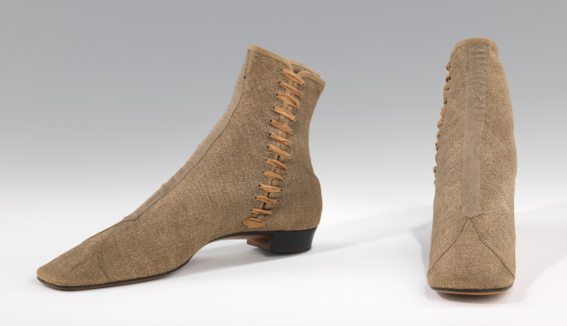 Beige Wildleder-Stiefel mit hellbraunen Schnürsenkeln, die in einer ordentlichen Schleife auf einem weißen Hintergrund gebunden sind, mit klassischem gerundetem Zeh und niedriger Absatz.