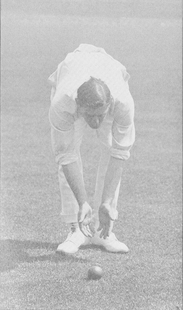 Ein Mann in einem weißen Cricket-Outfit steht bereit zum Spiel, mit einem Ball vor ihm in einem Schwarz-Weiß-Bild.
