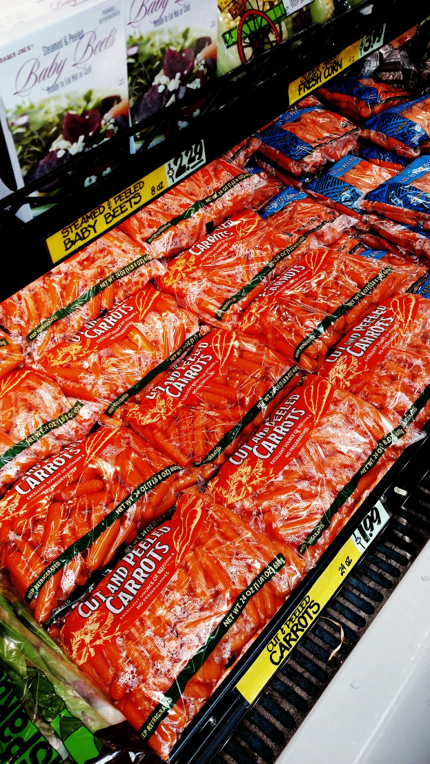 Geschäftsregal mit verschiedenen verpackten Lebensmitteln, darunter Gemüsepackungen, jeweils mit einem Preisschild.