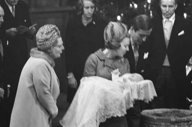 Schwarzes und weißes Foto von Queen Elizabeth II., die das neugeborene Prinz Charles h├Ąlt, mit Prinz Philip und anderen bei einer Weihnachtsbaumbeleuchtungszeremonie, ein Korb ist auf der rechten Seite sichtbar.