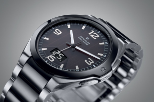 Close-up of a wristwatch with a black face, white numbers, and hands on a gray background.