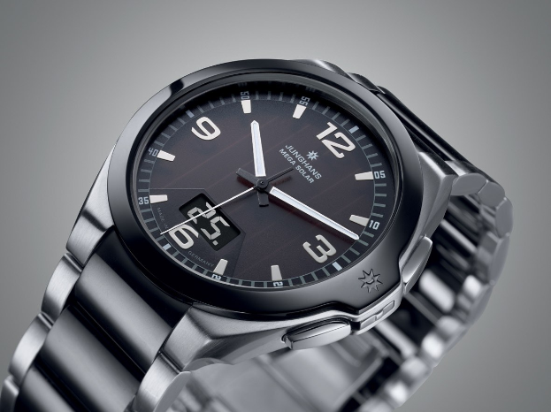 Close-up of a wristwatch with a black face, white numbers, and hands on a gray background.