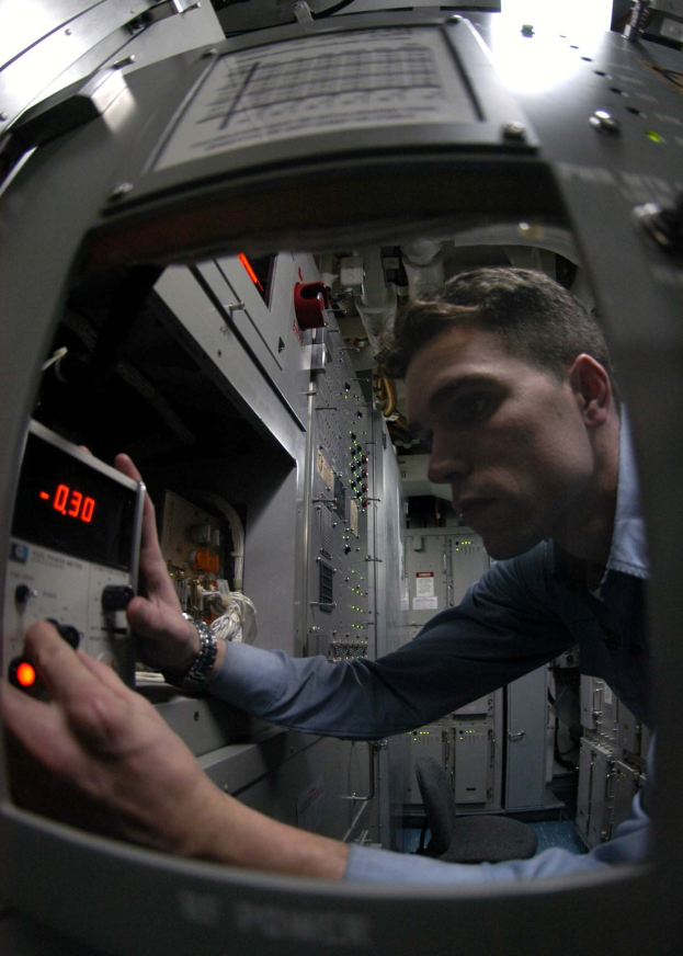 Ein Astronaut in einem Anzug untersucht einen Computerbildschirm in einer mit Geräten und einem Stuhl gefüllten Raumstation.