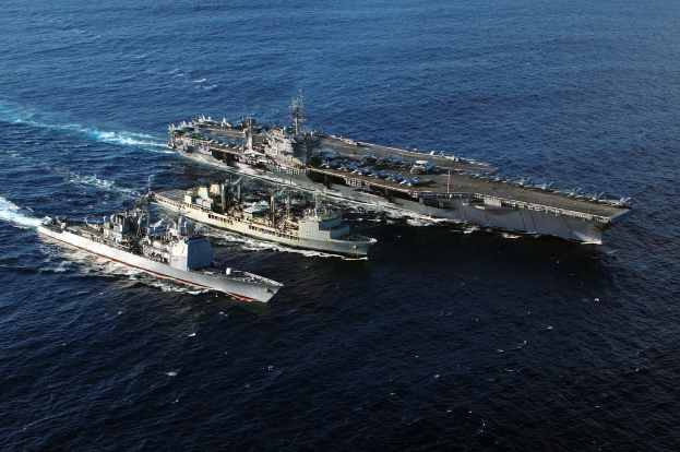 Zwei US-Kriegsschiffe, USS George H. W. Bush (CVN-68) und USS John C. Stennis, fahren im Arabischen Meer mit Sonnenlicht, das sich auf der Wasseroberfläche spiegelt.