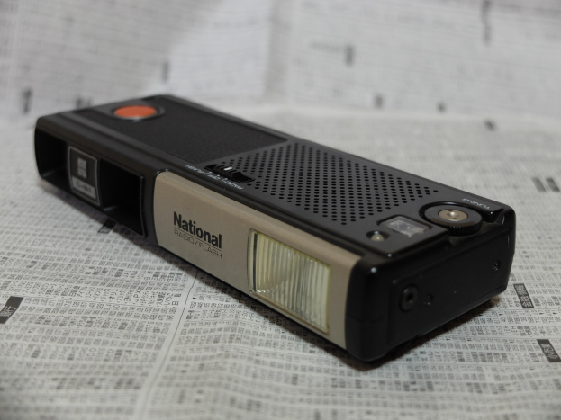 Ein schwarzes und cremefarbenes Radio mit schwarzem Gehäuse und cremefarbenen Akzenten auf einem Zeitungsblatt mit weißem Hintergrund.