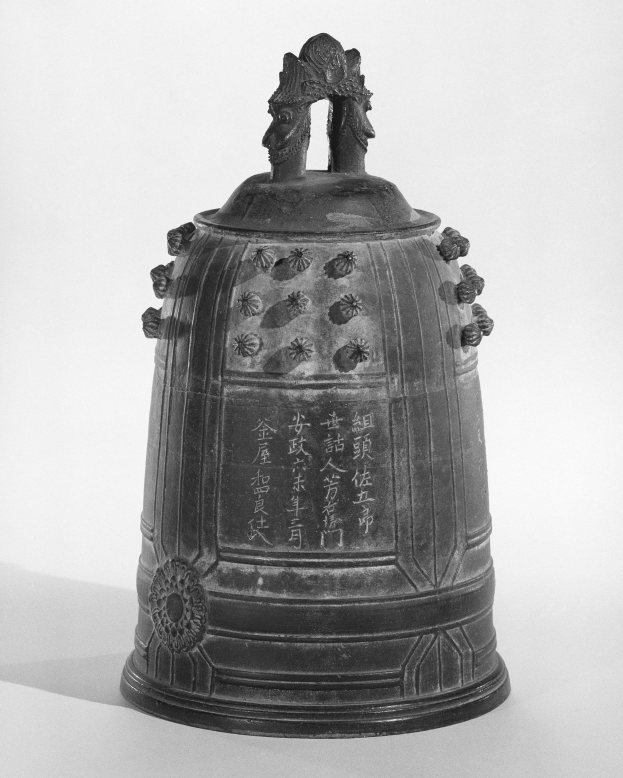 Ein Schwarz-Weiß-Foto einer Metallglocke mit chinesischer Schrift und kunstvollen Verzierungen.