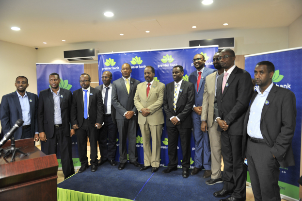 Eine Gruppe von Männern in Anzügen, die vor einem Rednerpult, einem Tisch, Bannern, einer Klimaanlage und Deckenlampen stehen und wahrscheinlich eine führende Bank darstellen.