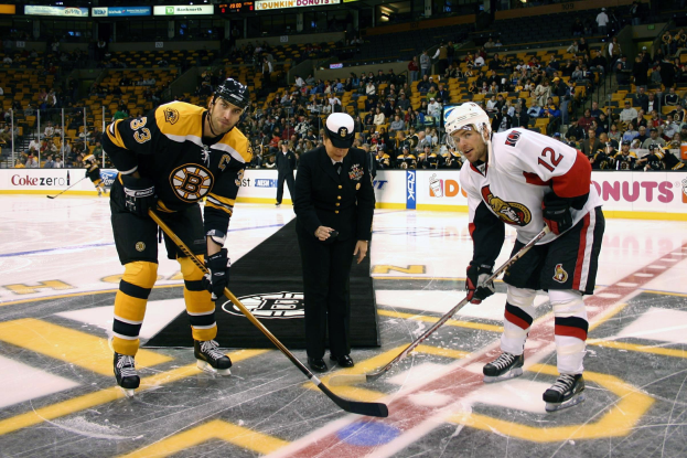 Eishockeyspiel zwischen den Boston Bruins und Ottawa Senators mit Spielern, Schiedsrichter, Zuschauern in den R├Ąngen, Werbetafeln und Eisbeleuchtung.